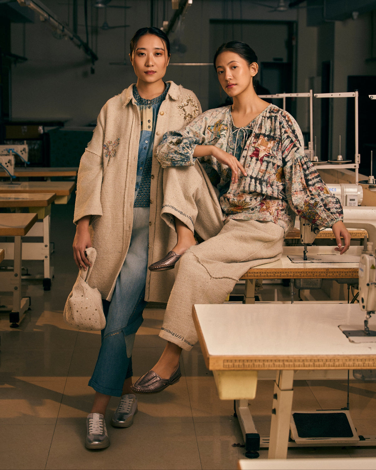 Two women standing in a workshop with sewing equipment.